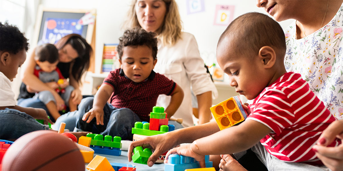 Children playing with building blocks while an adult supports them
